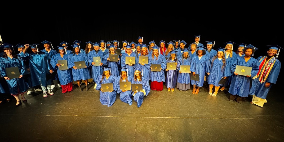 Students in blue caps and gowns pose for a group photo.