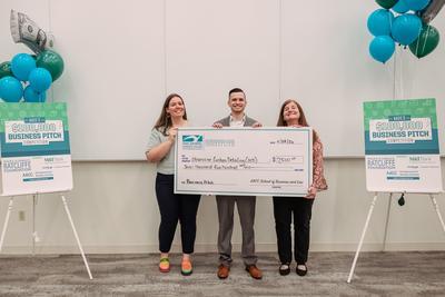 Kenneth Thomas holding a giant check with Hannah Gribbin and Stephanie Goldenberg.