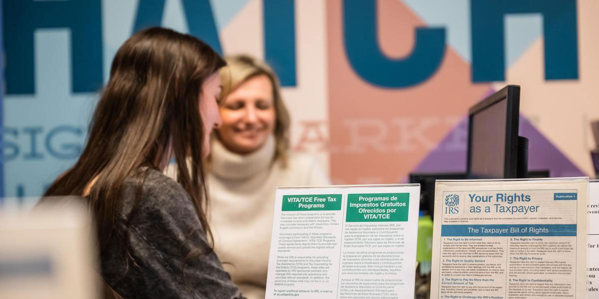 Volunteers in AACC's Volunteer Income Tax Assistance program chat behind a sign about taxpayer rights