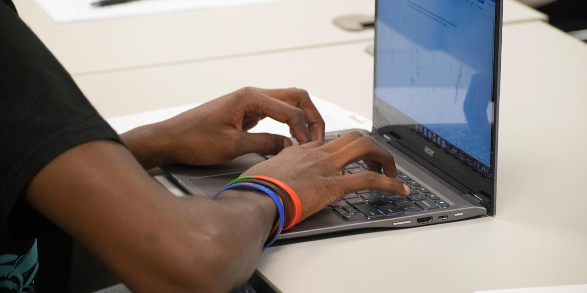 Student typing on laptop.