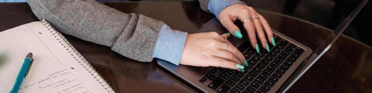 Student typing on a laptop and taking notes